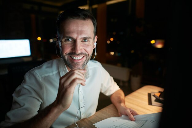 Retrato del empresario sonriente trabajando hasta tarde en su oficina