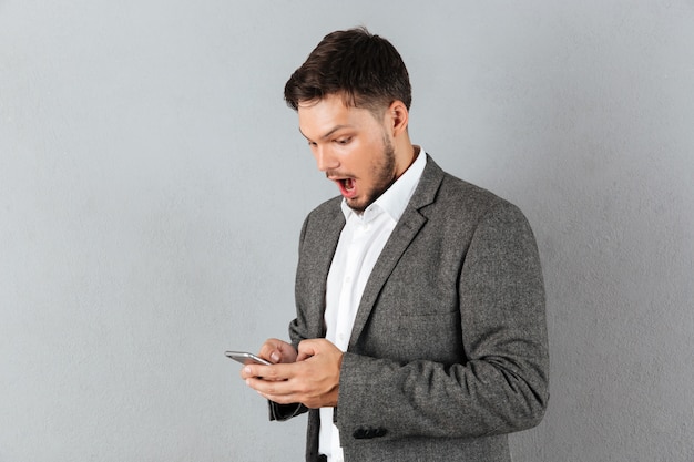 Retrato de un empresario sorprendido mirando el teléfono móvil