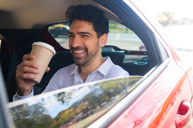 Retrato del empresario tomando café en su camino al trabajo en coche