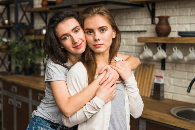Retrato de una encantadora joven pareja lesbiana de pie en la cocina