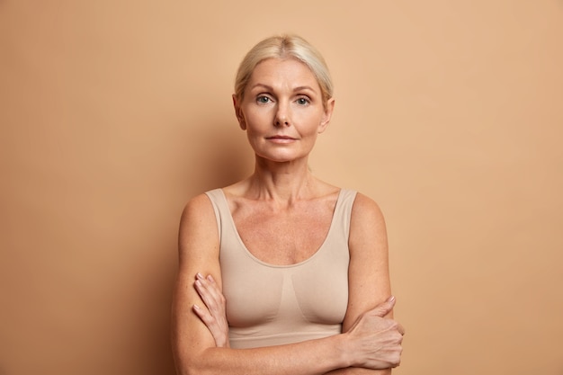 Retrato de encantadora mujer arrugada posando con los brazos cruzados