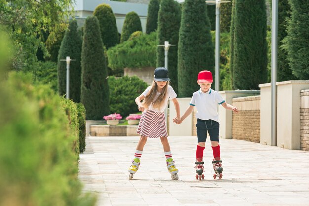 Retrato de una encantadora pareja de adolescentes patinando juntos sobre patines en el parque.