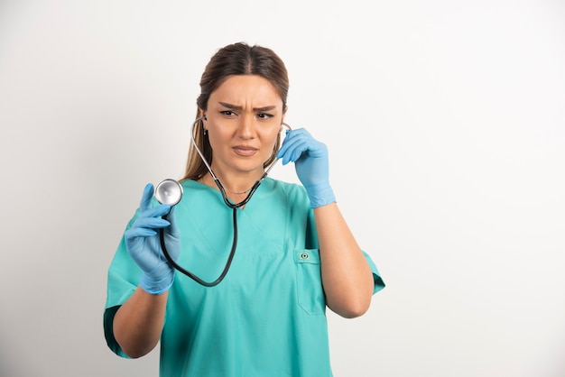 Retrato de una enfermera seria con guantes de látex y un estetoscopio.