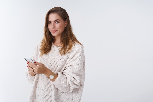 Retrato entusiasta atractiva mujer moderna leyendo noticias utilizando teléfonos inteligentes navegando por páginas web sosteniendo el teléfono móvil girando la cámara sonriendo encantado despreocupado, mirando relajado