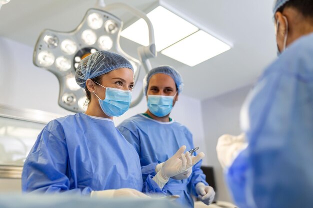 Retrato del equipo de cirujanos multiétnicos trabajando en un quirófano Varios médicos rodeando al paciente en la mesa de operaciones durante su trabajo