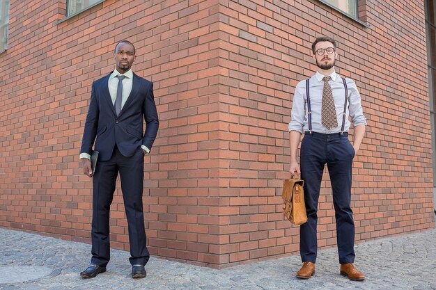 Retrato de equipo de negocios multiétnico. Dos hombres de pie con el telón de fondo de la ciudad. Un hombre es afroamericano, el otro es europeo. concepto de éxito empresarial