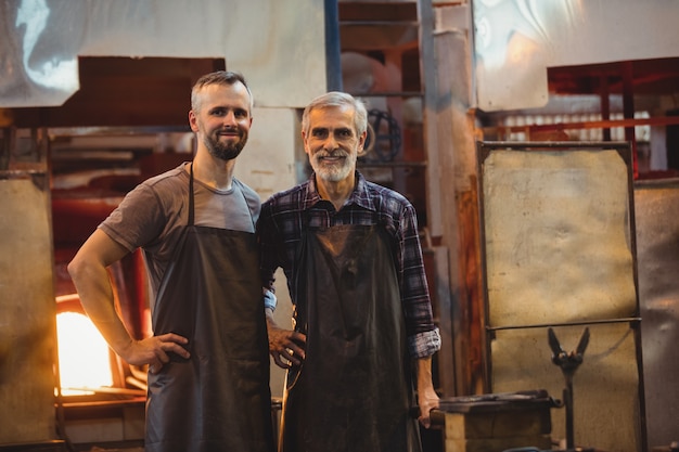 Retrato del equipo de sopladores de vidrio con las manos en la cadera