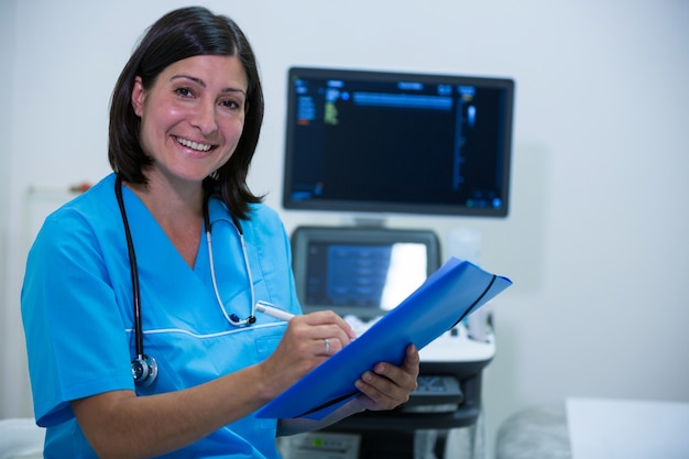 Retrato de la escritura mujer médico en el portapapeles