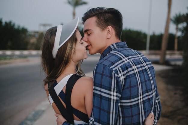 Retrato de espalda alegre pareja de enamorados caminando por la carretera en los países tropicales. Sonriendo con los ojos cerrados, felicidad, besos, viajar juntos.