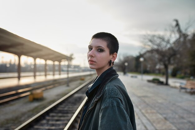 Retrato estético pop punk de mujer posando en la estación de tren