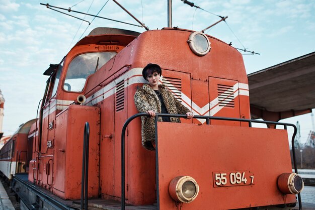 Retrato estético pop punk de mujer posando junto a una locomotora