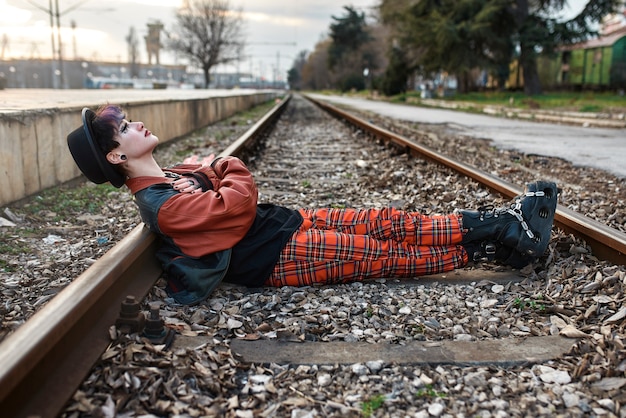 Retrato estético pop punk de mujer posando en vías de tren