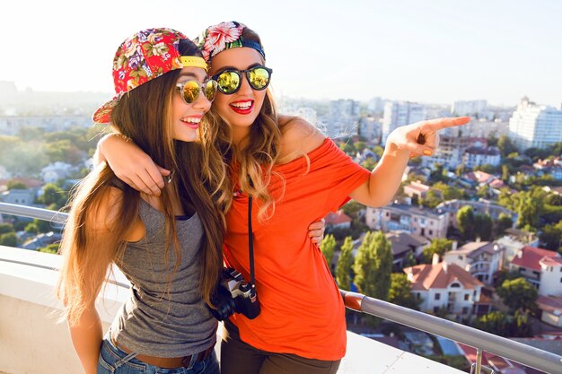 Retrato de estilo de vida al aire libre de dos mejores amigas hermanas chicas posando en el techo