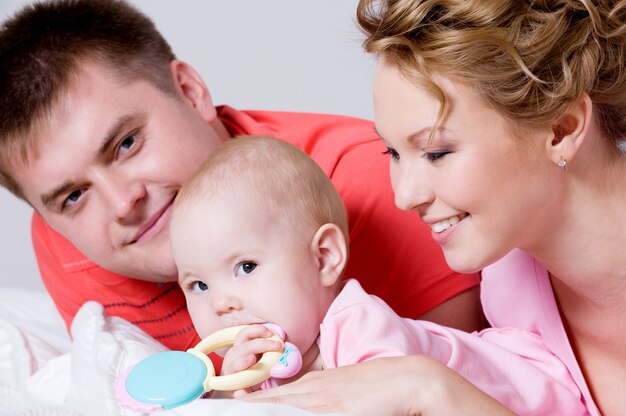 Retrato de estilo de vida de la hermosa joven familia feliz acostado en la cama en casa