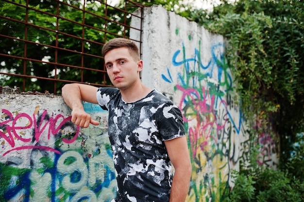 Retrato de estilo de vida de hombre guapo posando en la calle de la ciudad con pared de graffiti