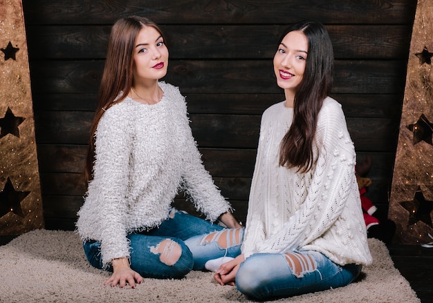 Retrato de estilo de vida interior de dos amigas divertidas bastante jóvenes abrazos sonriendo y divirtiéndose