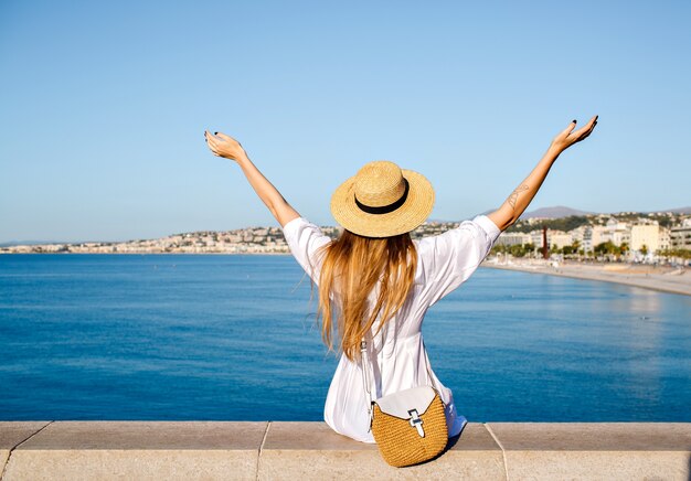 Retrato de estilo de vida de verano de la mujer turista bastante rubia posando en el punto de vista en la Riviera francesa