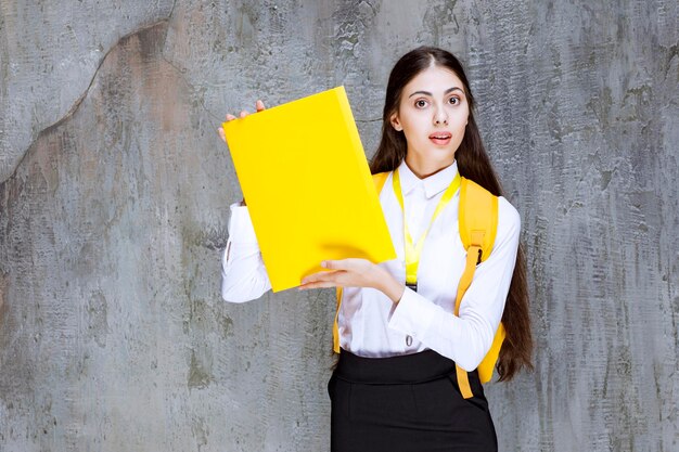 Retrato de estudiante bonita con cuaderno amarillo posando para la cámara. foto de alta calidad