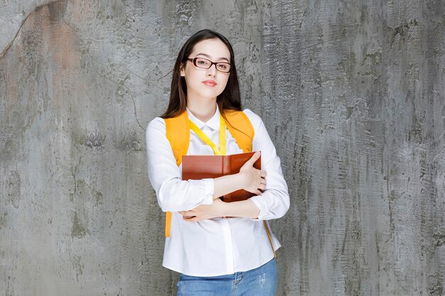 Retrato de una estudiante con gafas sosteniendo un libro. foto de alta calidad