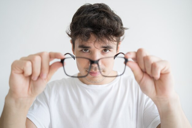 Retrato del estudiante joven concentrado que mira las lentes