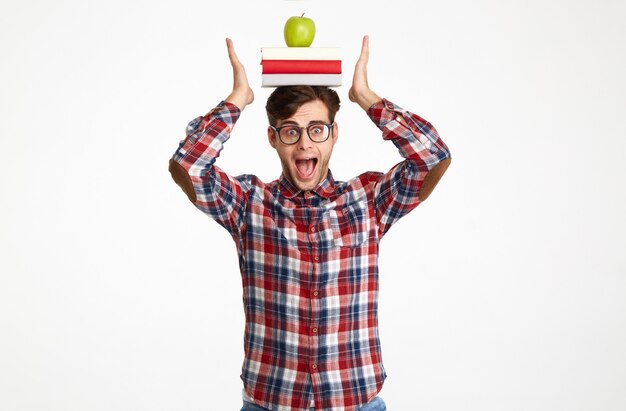 Retrato de un estudiante masculino divertido sosteniendo libros