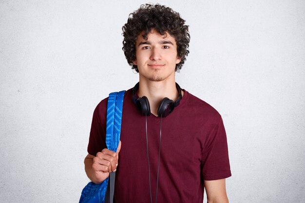 Retrato de estudiante masculino inconformista encantado con cabello crujiente