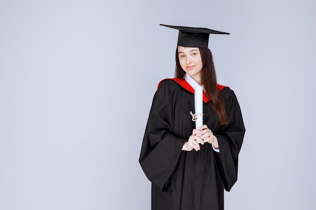 Retrato de estudiante de posgrado en bata mostrando certificado universitario. Foto de alta calidad