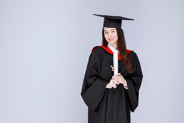 Retrato de estudiante de posgrado en bata mostrando certificado universitario. Foto de alta calidad