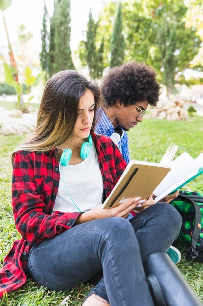 Retrato de una estudiante sentada con su amiga estudiando juntos en el parque