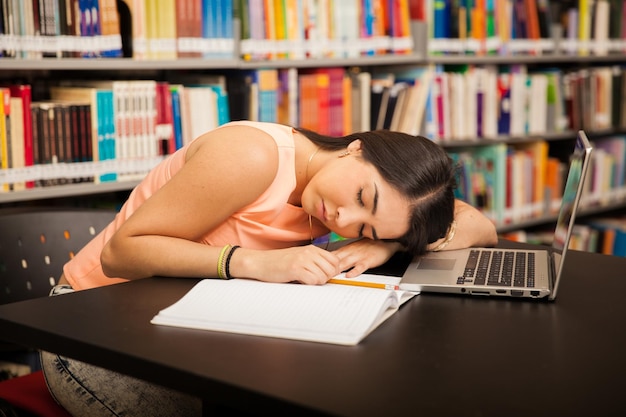 Retrato de un estudiante universitario latino que se siente cansado y abrumado en la escuela y toma una siesta