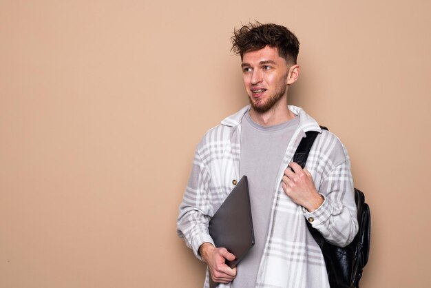 Retrato de estudiante varón pensativo sobre fondo beige