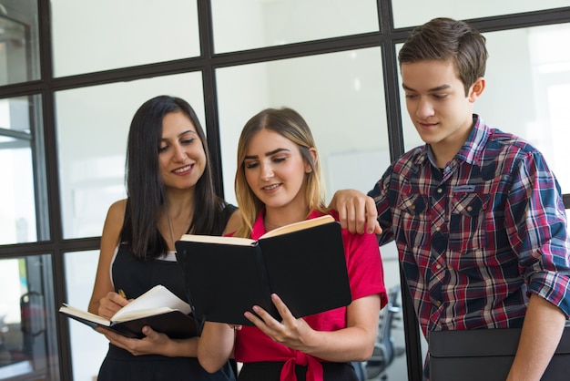 Foto gratuita retrato de estudiantes jóvenes felices compartiendo tareas en la universidad