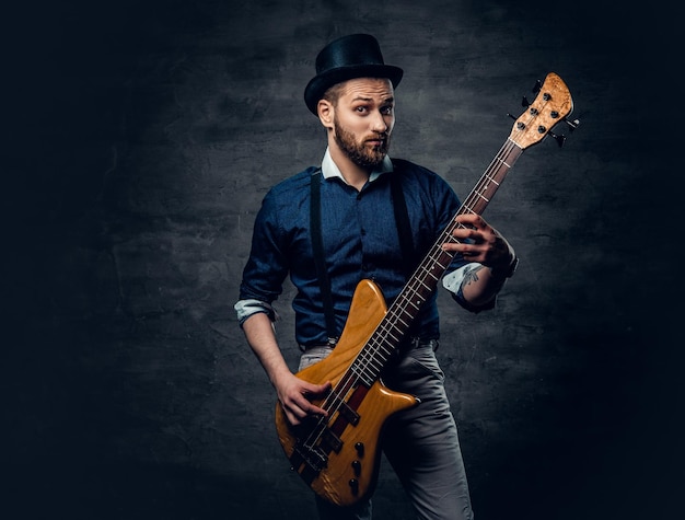 Foto gratuita retrato de estudio del bajista hipster vestido con sombrero cilíndrico.