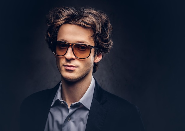 Retrato de estudio de un carismático macho sensual con cabello elegante y gafas de sol