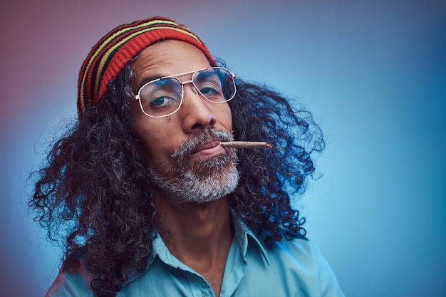 Retrato de estudio de cigarrillos fumadores masculinos rastafari africanos. Aislado sobre un fondo azul.