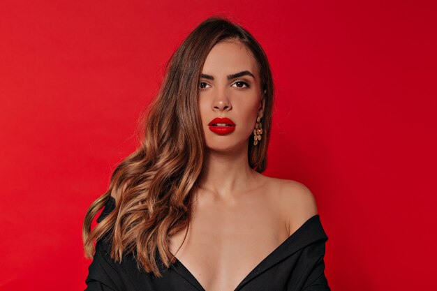 Retrato de estudio de dama elegante elegante con maquillaje de noche en vestido negro con hombros descubiertos