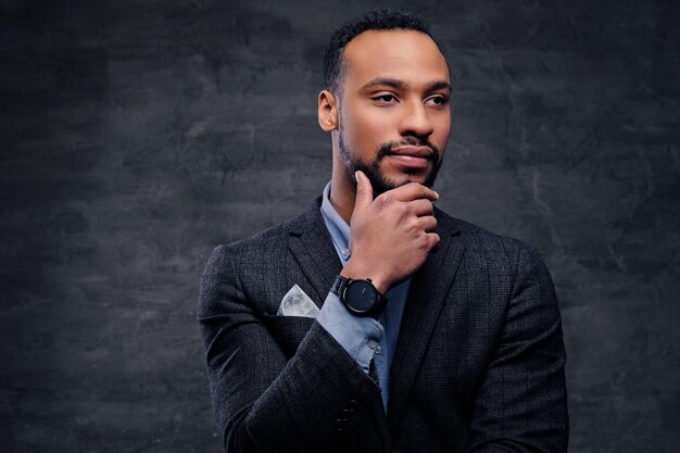 Retrato de estudio de un elegante hombre negro americano vestido con un traje sobre fondo de viñeta gris.