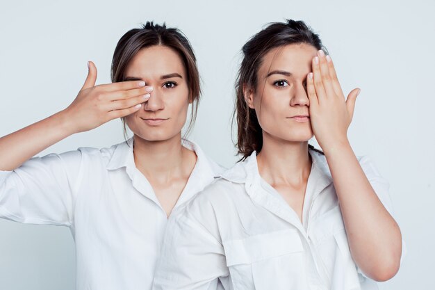 Retrato de estudio de hermanas gemelas jóvenes en gris