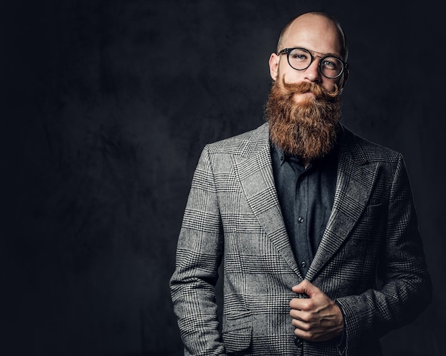 Retrato de estudio de hombre barbudo pelirrojo con anteojos antiguos vestido con una chaqueta de lana.