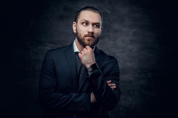 Retrato de estudio de un hombre barbudo vestido con una chaqueta azul sobre un fondo de viñeta gris.