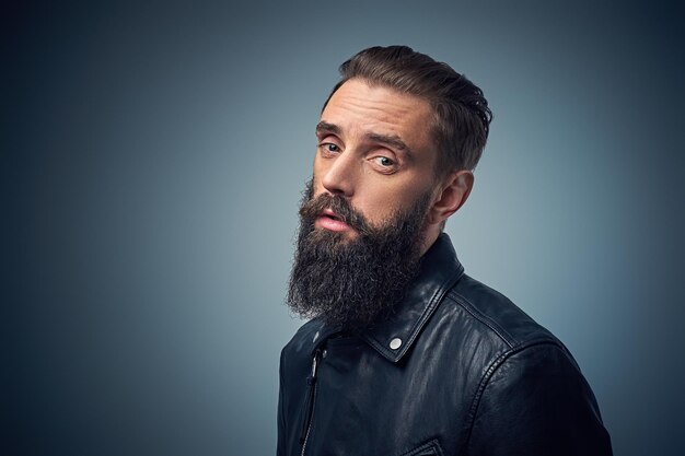 Retrato de estudio de hombre barbudo vestido con chaqueta de cuero negro.