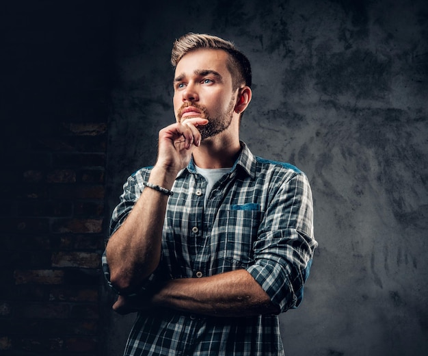 Retrato de estudio de hombre hipster barbudo pensativo sobre fondo gris.