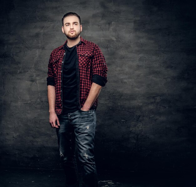 Retrato de estudio de un hombre hipster barbudo vestido con una camisa de lana roja sobre fondo gris.