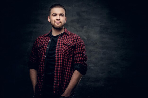 Retrato de estudio de un hombre hipster barbudo vestido con una camisa de lana roja sobre fondo gris.