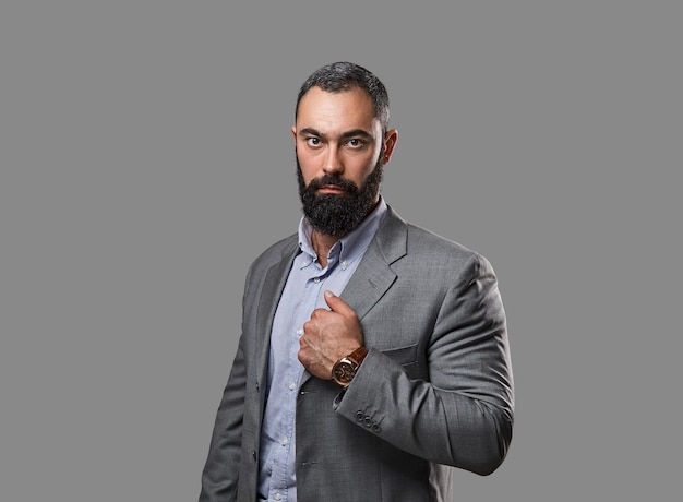 Retrato de estudio de un hombre serio y barbudo vestido con un traje.