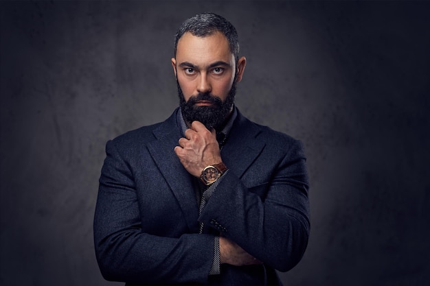 Retrato de estudio de un hombre serio y barbudo vestido con un traje.