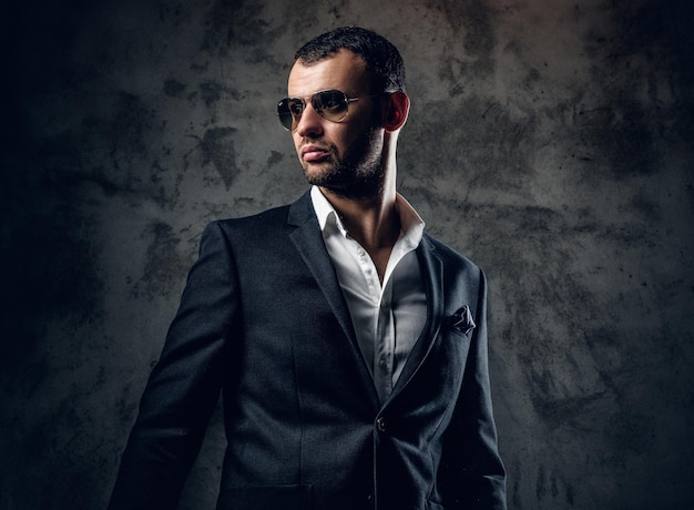 Retrato de estudio de un hombre serio y moderno con camisa blanca y chaqueta de negocios con fondo gris.