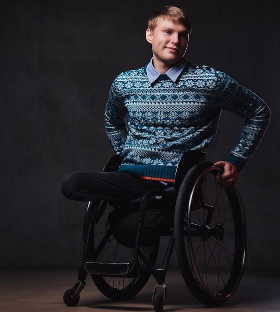 Retrato de estudio de un hombre en silla de ruedas sobre fondo gris.