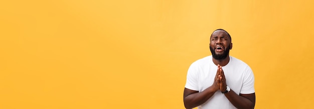 Foto gratuita retrato de estudio de un joven afroamericano con camisa blanca tomados de la mano en oración mirando el