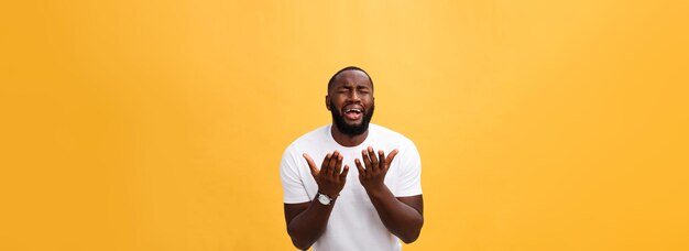 Retrato de estudio de un joven afroamericano con camisa blanca tomados de la mano en oración mirando el